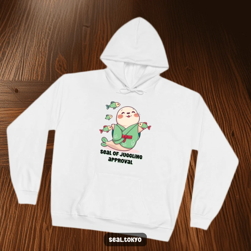 Funny seal in a vibrant green kimono, skillfully juggling three small fish, designed on a soft, warm hoodie for maximum comfort and humor.